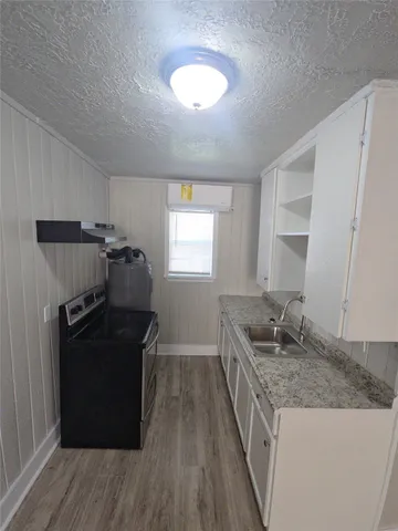a kitchen with granite countertop a refrigerator and a stove top oven
