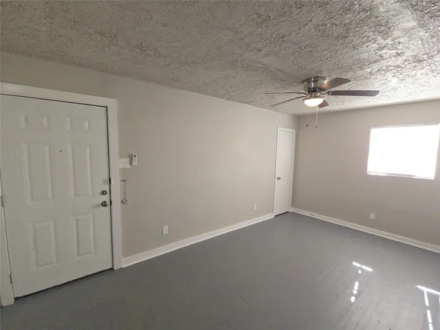 an empty room with fan and windows