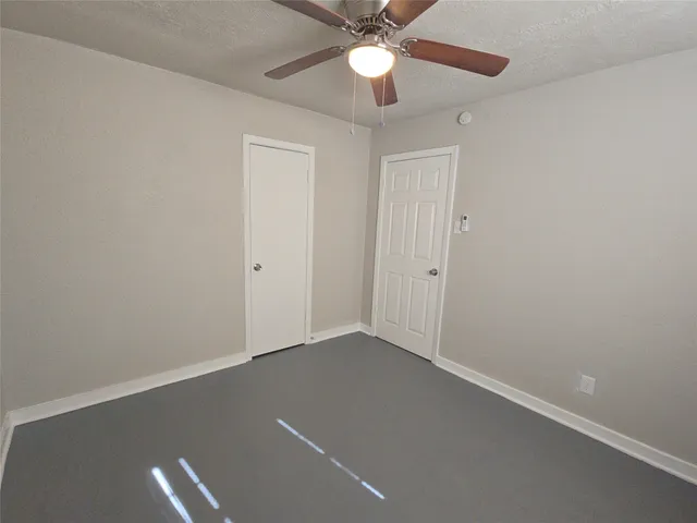 an empty room with a chandelier fan and closet