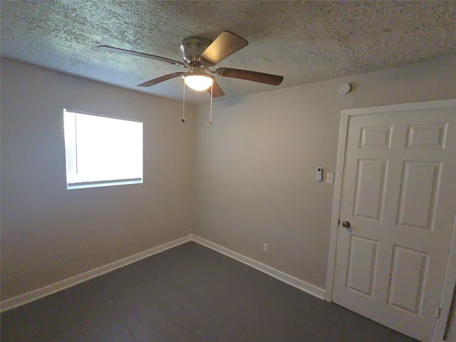 an empty room with a window and a fan