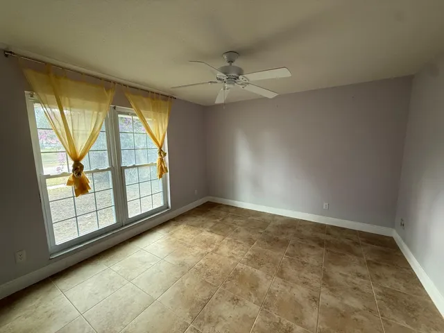 an empty room with windows and ceiling fan