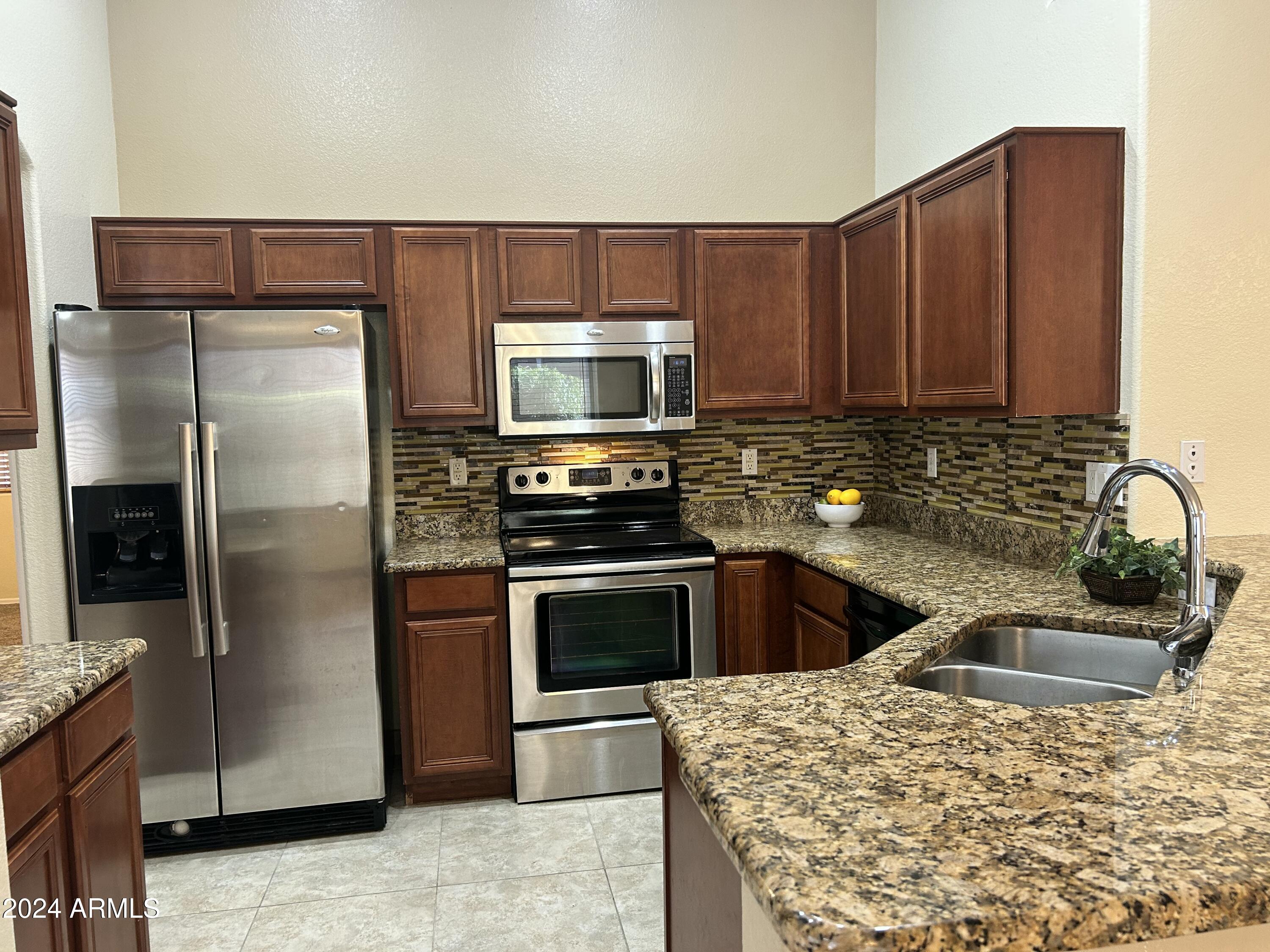 8143 West Marco Polo Road Peoria, AZ 85382 - Photo 6 of 29 a kitchen with stainless steel appliances granite countertop a refrigerator a stove and a sink