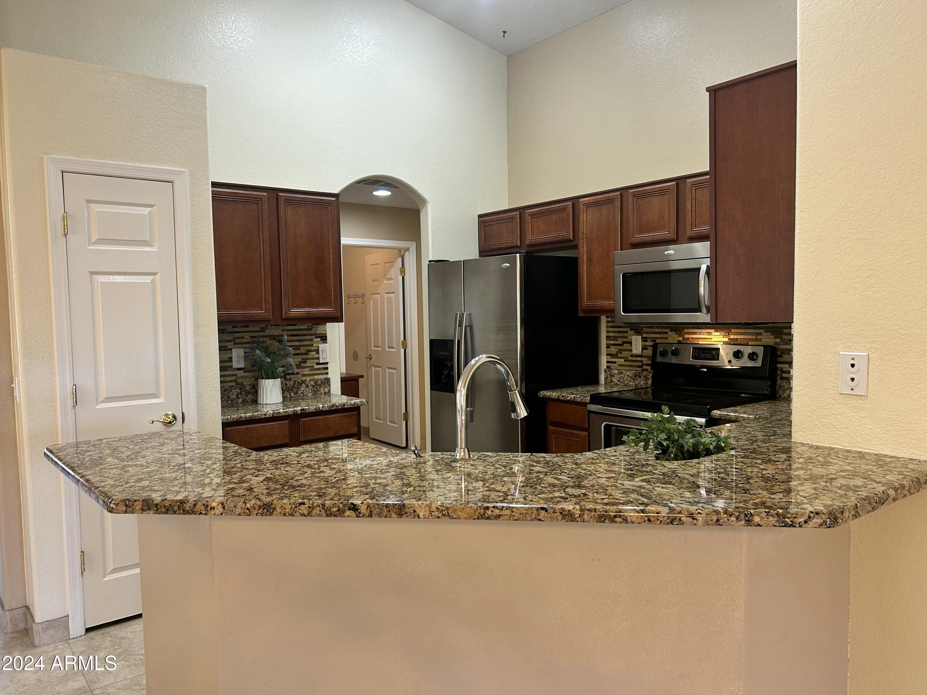 8143 West Marco Polo Road Peoria, AZ 85382 - Photo 7 of 29 a kitchen with kitchen island granite countertop a refrigerator a stove and a sink
