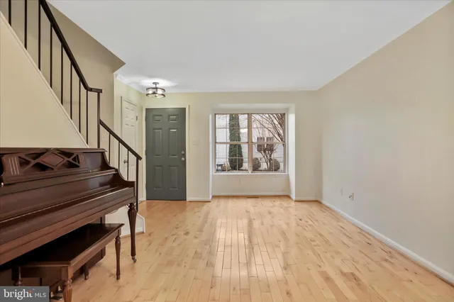 a view of an empty room with wooden floor stairs and a window