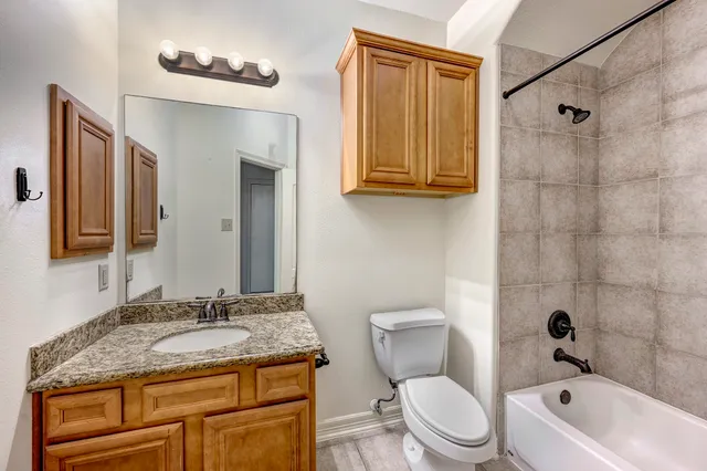 a bathroom with a granite countertop sink toilet and shower