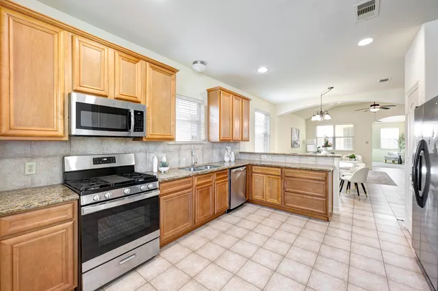 a kitchen with stainless steel appliances granite countertop a stove a sink and a microwave