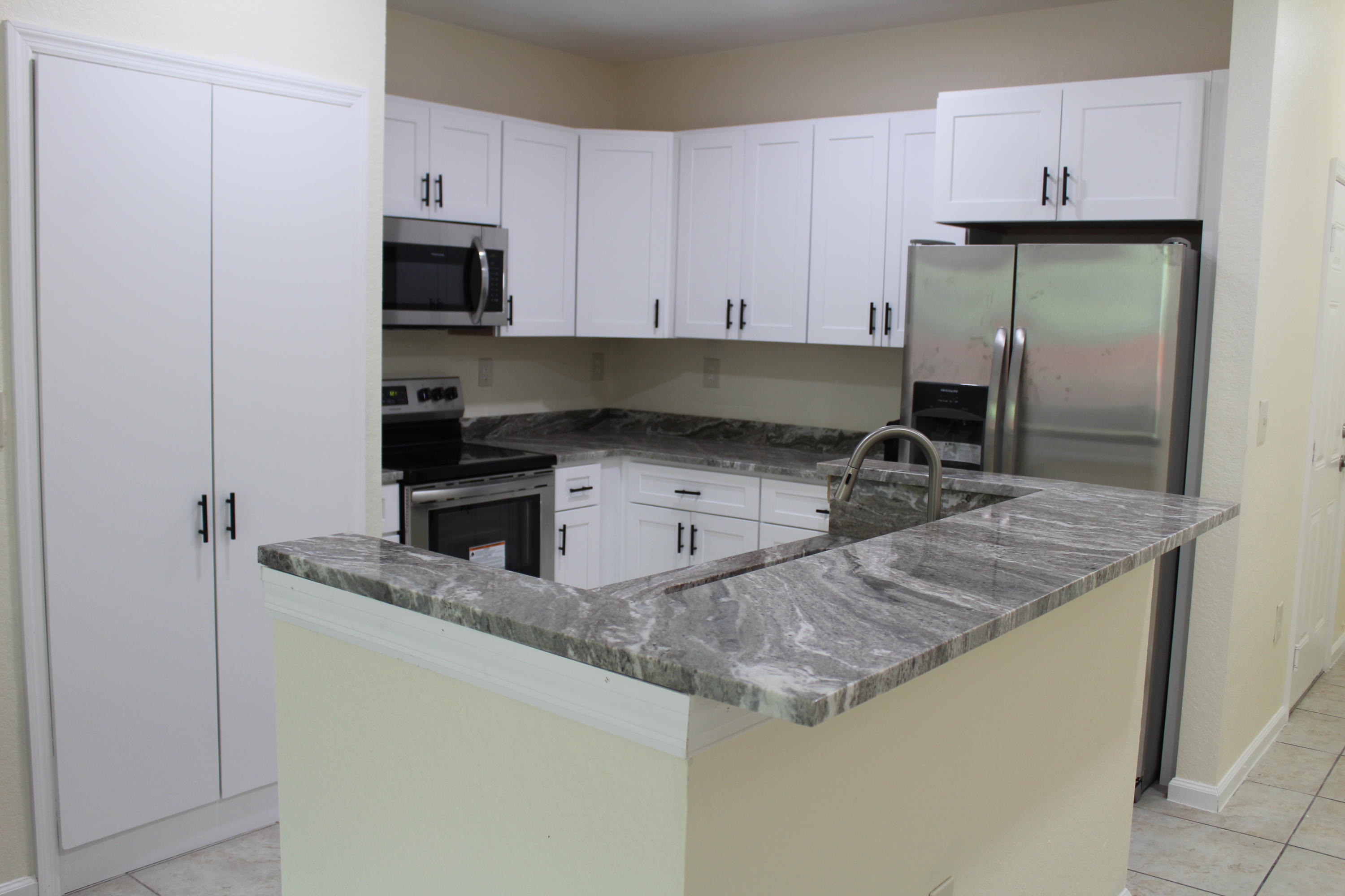 6375 Landings Way, Unit 6375 Tamarac, FL 33321 - Photo 2 of 14 a kitchen with granite countertop a sink a stove and a refrigerator