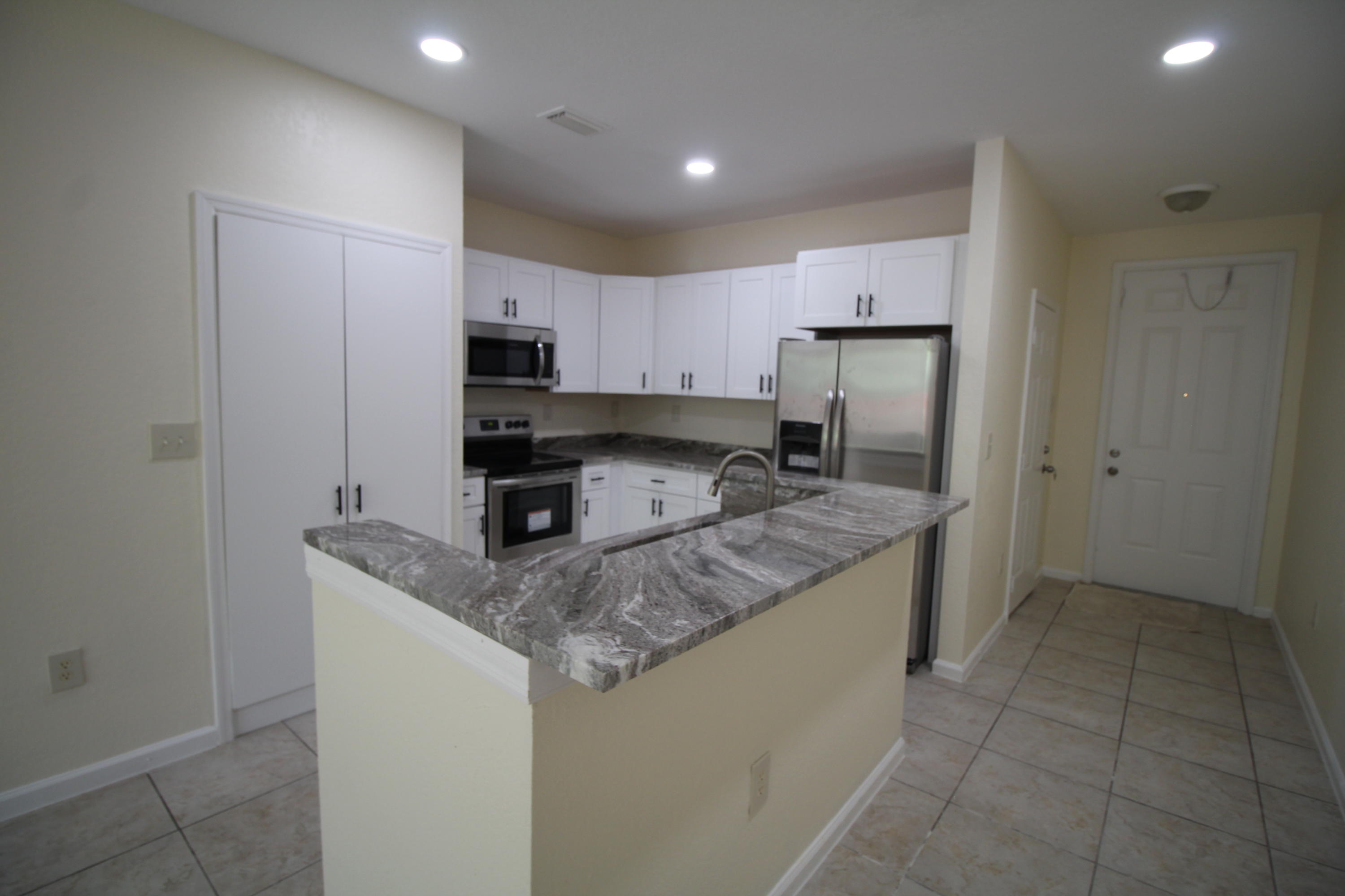 6375 Landings Way, Unit 6375 Tamarac, FL 33321 - Photo 3 of 14 a kitchen with granite countertop a refrigerator and a stove top oven