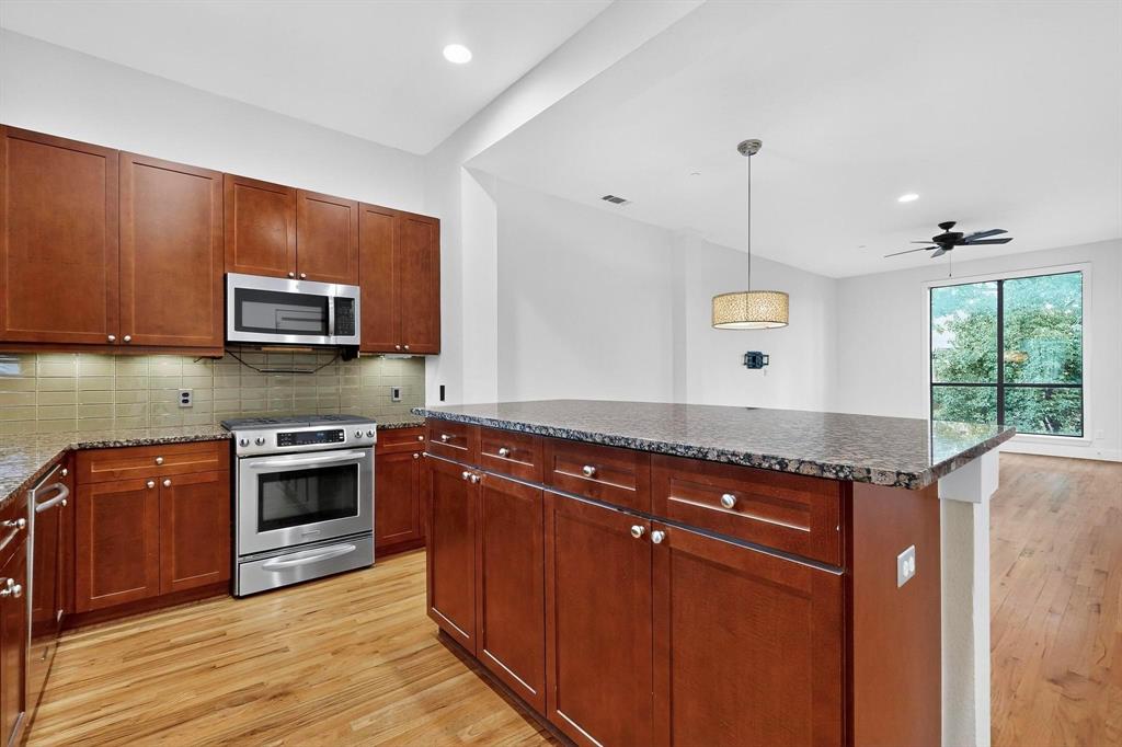 4211 Rawlins Street, Unit 528 Dallas, TX 75219 - Photo 4 of 14 Kitchen featuring wood-finish cabinetry, granite countertops, stainless steel appliances, and a tiled backsplash