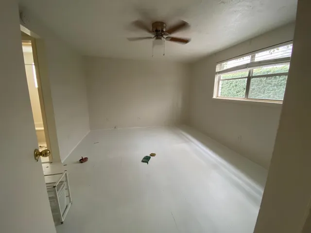 an empty room with a window and a ceiling fan