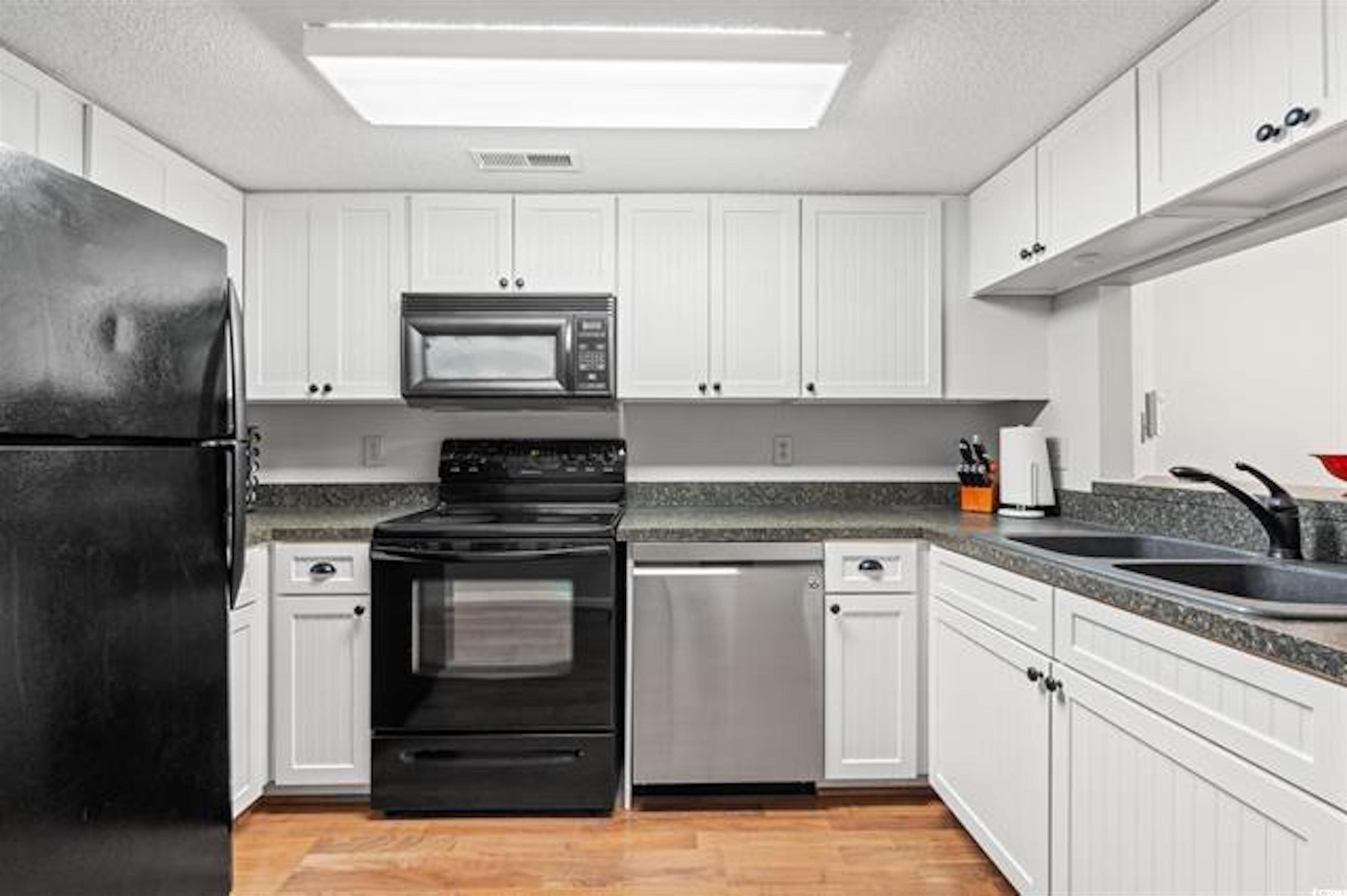 1100 Possum Trot Road, Unit B206 North Myrtle Beach, SC 29582 - Photo 6 of 16 Kitchen with white cabinetry, a sink, light wood f