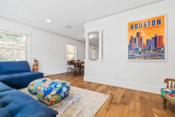 a living room with furniture and a dining table with wooden floor