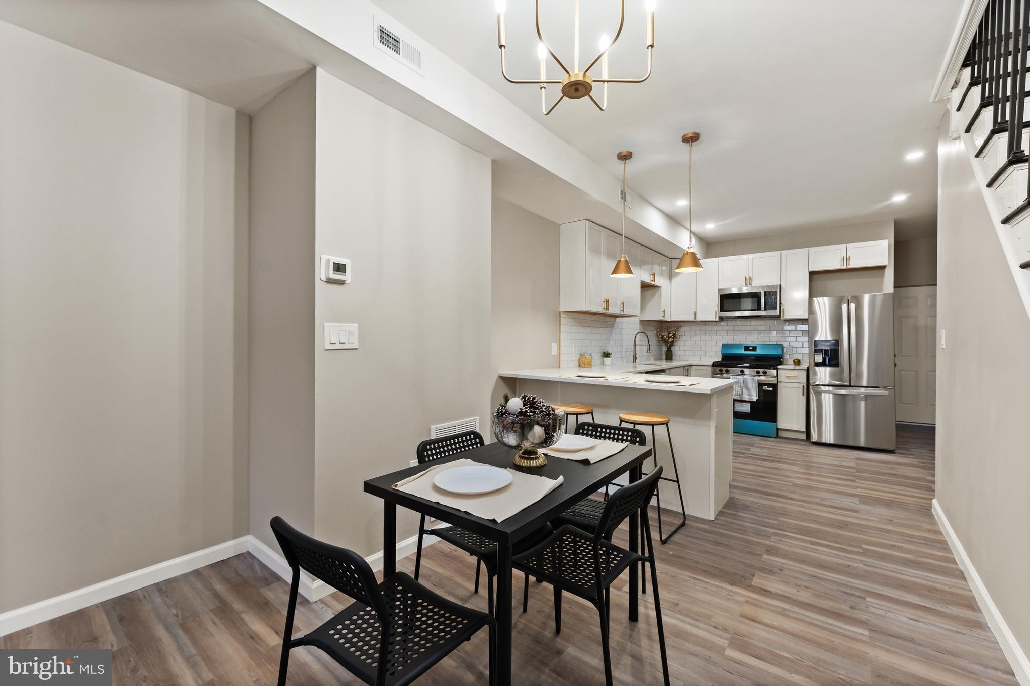 602 Denison Street Baltimore, MD 21229 - Photo 3 of 17 a kitchen with stainless steel appliances kitchen island granite countertop a dining table chairs and a refrigerator