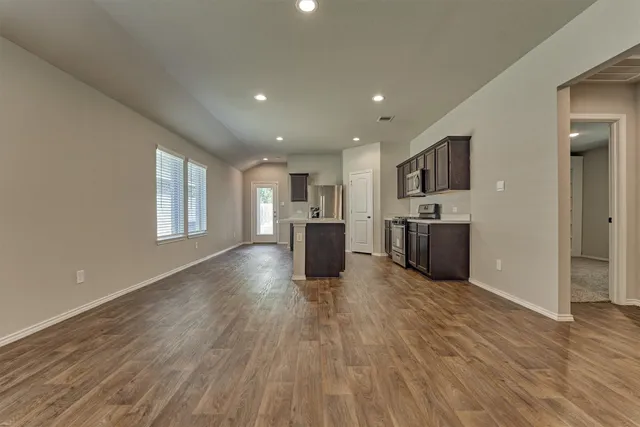 a living room with stainless steel appliances kitchen island hardwood floor and a large window