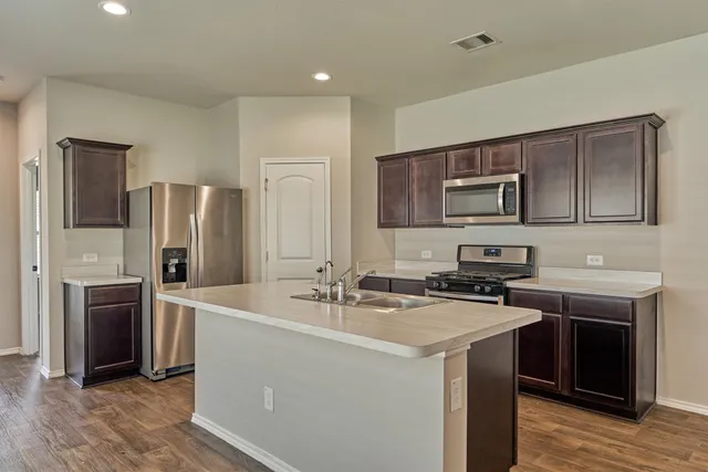 a kitchen that has a sink cabinets and stainless steel appliances