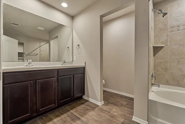 a bathroom with a double vanity sink a mirror and a bathtub