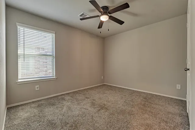 an empty room with a window and a fan