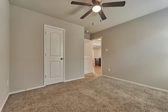 an empty room with fan walk in closet with a mirror