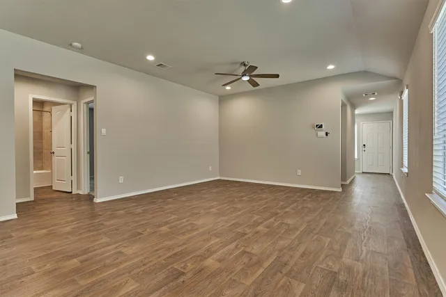 a view of empty room with wooden floor and fan