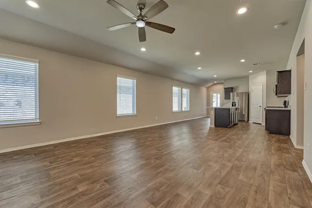 a view of an empty room with a window and wooden floor