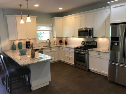 a kitchen with a sink white cabinets and stainless steel appliances