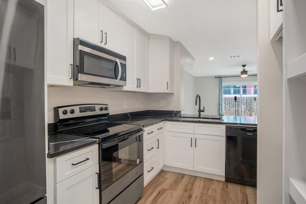 618 West Collins Street Denton, TX 76201 - Photo 11 of 25 Kitchen featuring appliances with stainless steel finishes, light wood finished floors, white cabinetry, ceiling fan, and a peninsula