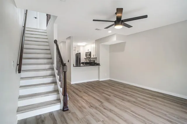 a view of empty room with wooden floor and ceiling fan