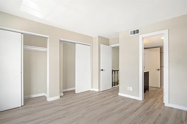 a view of an empty room with wooden floor and closet
