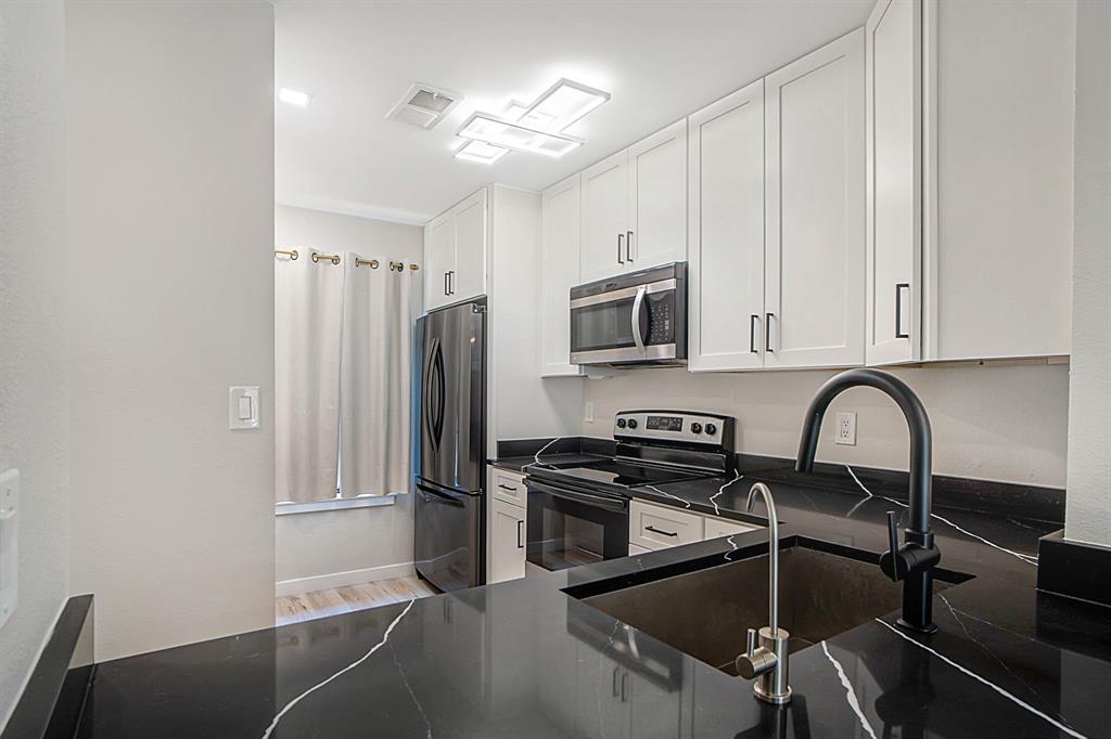 618 West Collins Street Denton, TX 76201 - Photo 8 of 25 Kitchen with stainless steel appliances, white cabinets, light wood finished floors, and dark stone countertops