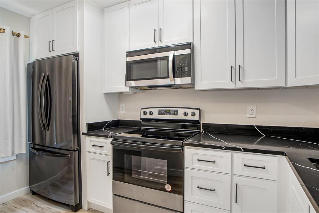618 West Collins Street Denton, TX 76201 - Photo 8 of 25 a kitchen with stainless steel appliances granite countertop white cabinets and a stove a refrigerator with wooden floors