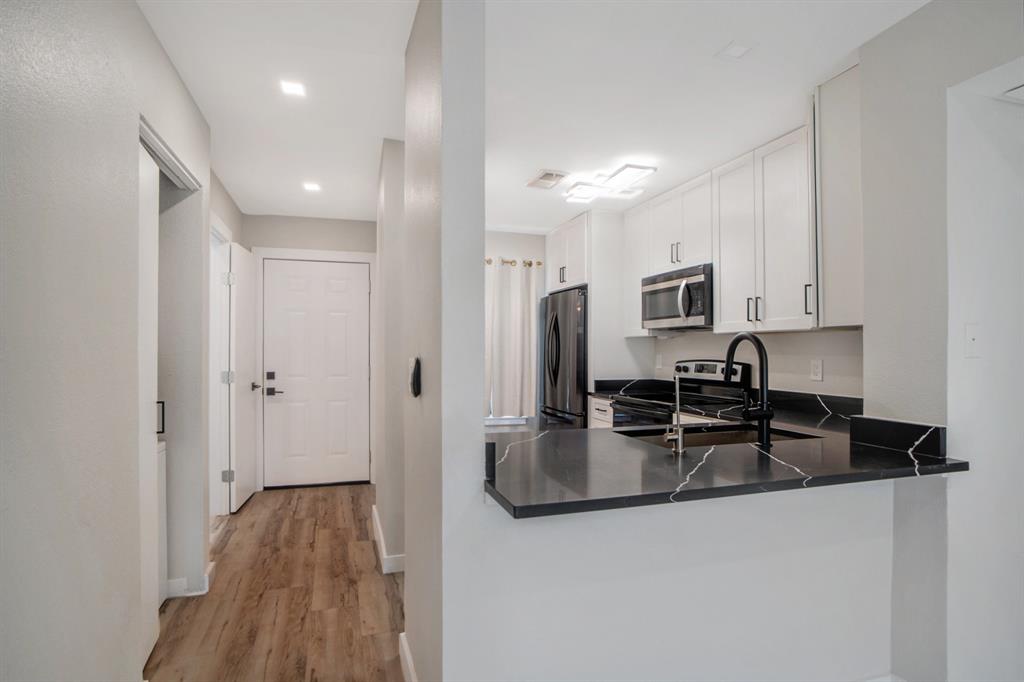 618 West Collins Street Denton, TX 76201 - Photo 9 of 25 Kitchen with stainless steel appliances, light wood-style floors, white cabinets, a peninsula, and recessed lighting