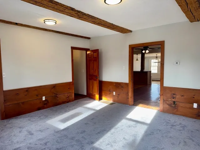 a view of an empty room with wooden floor fireplace and a window