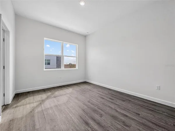 a view of an empty room with wooden floor and window