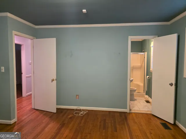 an empty room with wooden floor and a bathroom