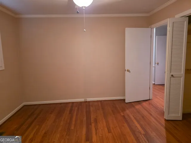 a view of an empty room with wooden floor and closet