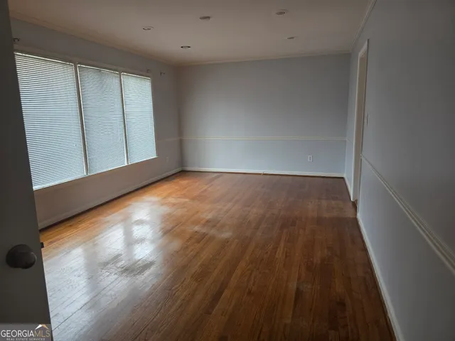 a view of an empty room with wooden floor and a window
