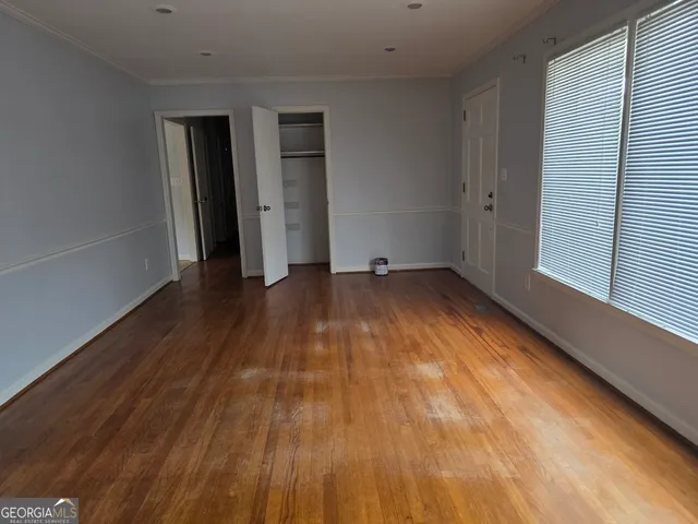 a view of an empty room with wooden floor and a window