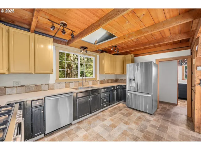 a large kitchen with stainless steel appliances kitchen island granite countertop a refrigerator and a sink