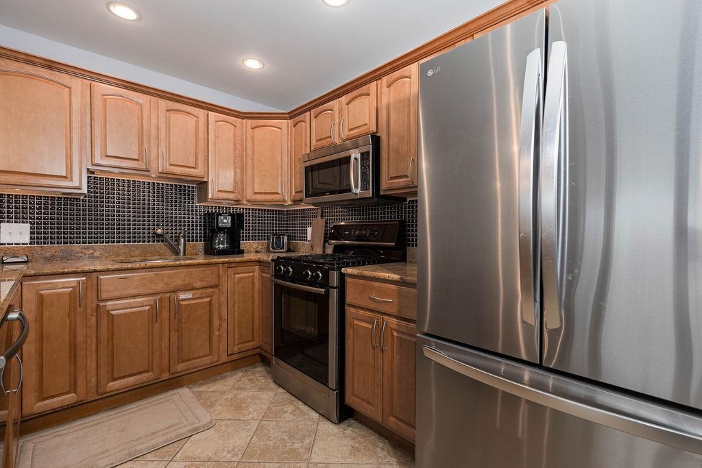 415 East Heather Road, Unit 106 Wildwood Crest, NJ 08260 - Photo 32 of 41 a kitchen with stainless steel appliances granite countertop a refrigerator a stove top oven a sink and dishwasher