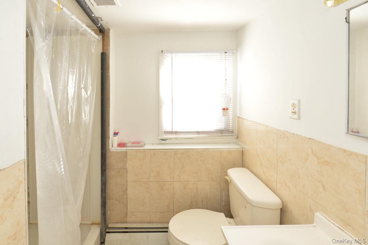 7 South Oak Street Spring Valley, NY 10977 - Photo 12 of 24 a white toilet sitting next to a bathroom sink and vanity