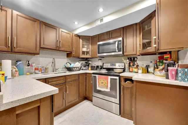 a kitchen with stainless steel appliances granite countertop a sink stove refrigerator and cabinets