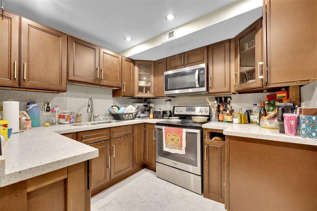 a kitchen with stainless steel appliances granite countertop a sink stove refrigerator and cabinets