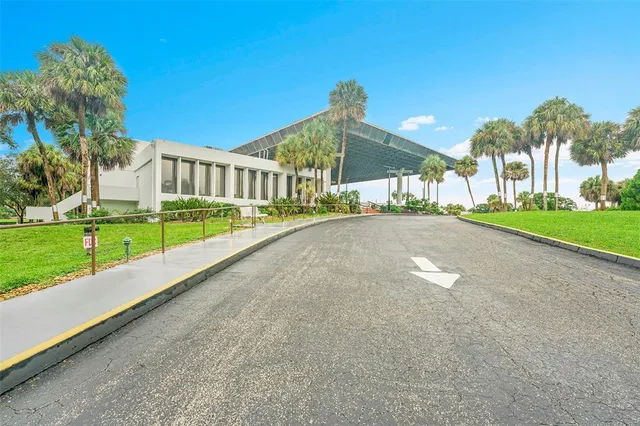 a view of a house with a yard and palm trees