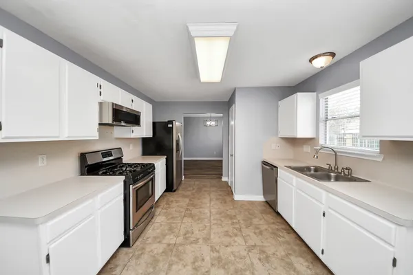 a large kitchen with stainless steel appliances granite countertop a sink and dishwasher a stove top oven with wooden floor