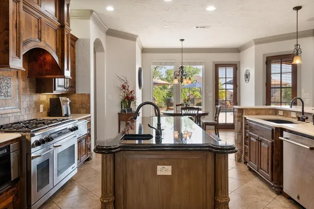 a kitchen with kitchen island granite countertop a stove a sink dishwasher and white cabinets with wooden floor