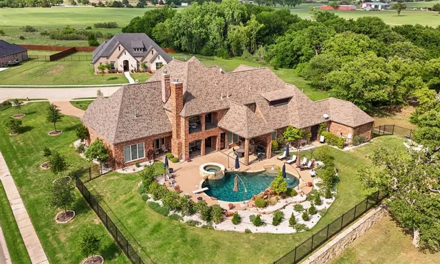 an aerial view of a house with swimming pool a yard and lake view