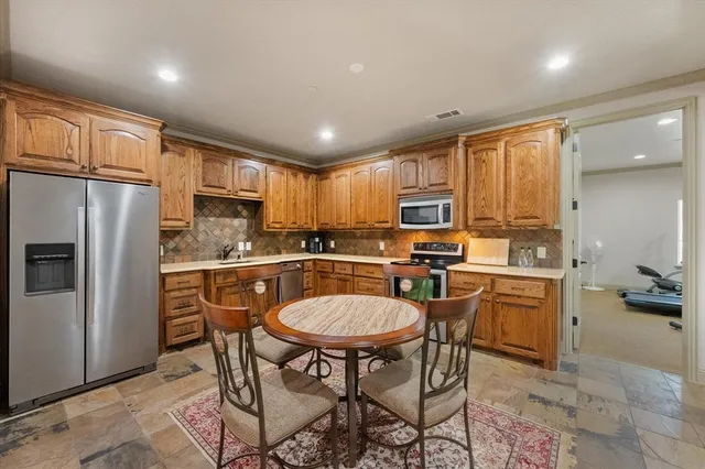 a kitchen with a refrigerator a stove microwave cabinets and chairs