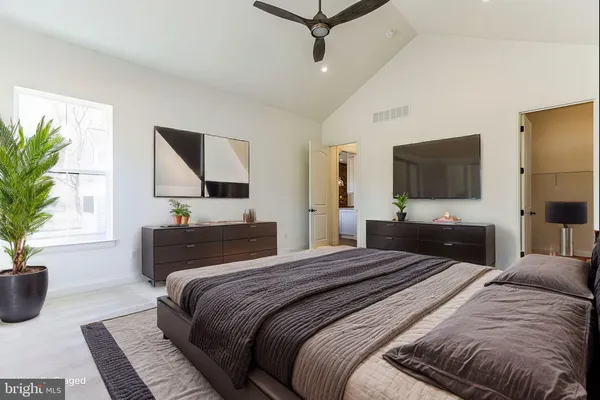 a bedroom with a large bed a flat tv screen and a potted plant