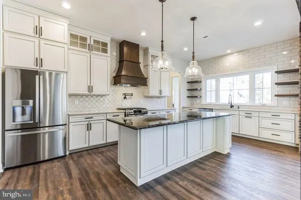a kitchen with stainless steel appliances granite countertop a sink a stove a refrigerator and island with wooden floor