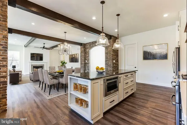 a kitchen with stainless steel appliances a stove top oven a sink dishwasher a dining table and chairs with wooden floor